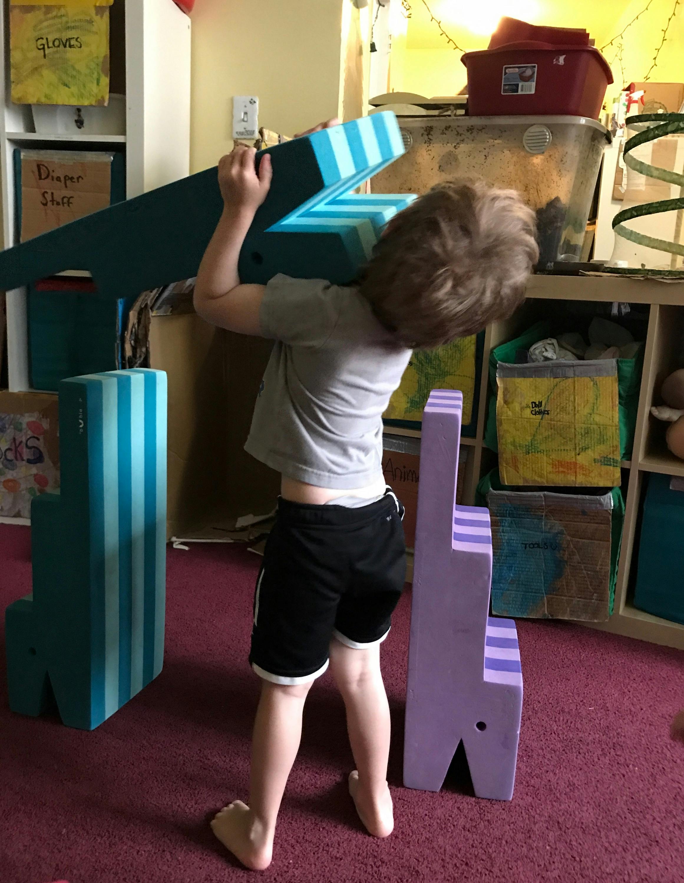 Child carrying a large striped letter Z-shaped object