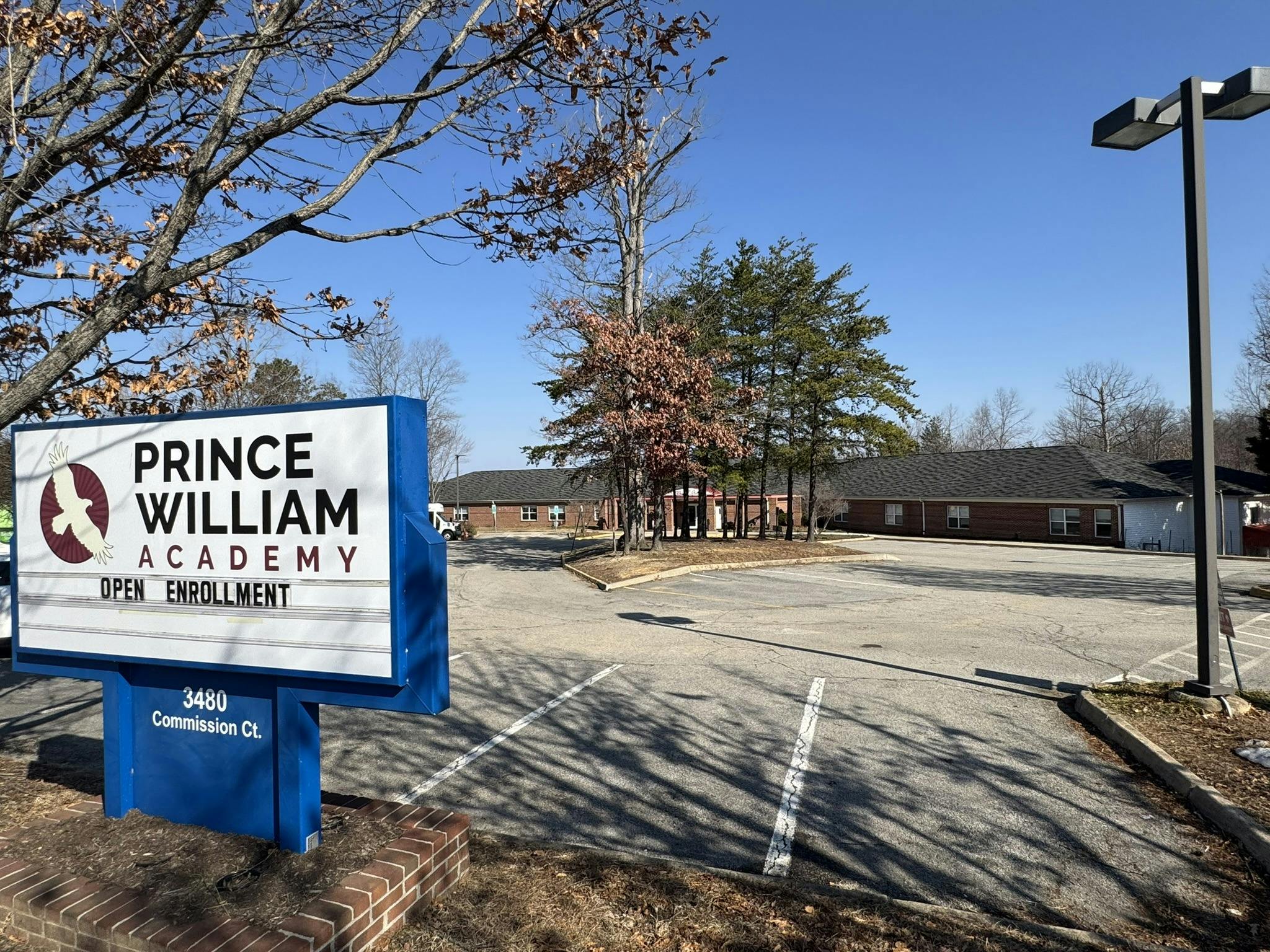 Prince William Academy sign with "Open Enrollment" message, parking lot, and buildings