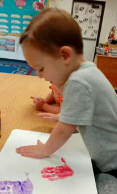 Child making a handprint with paint on paper