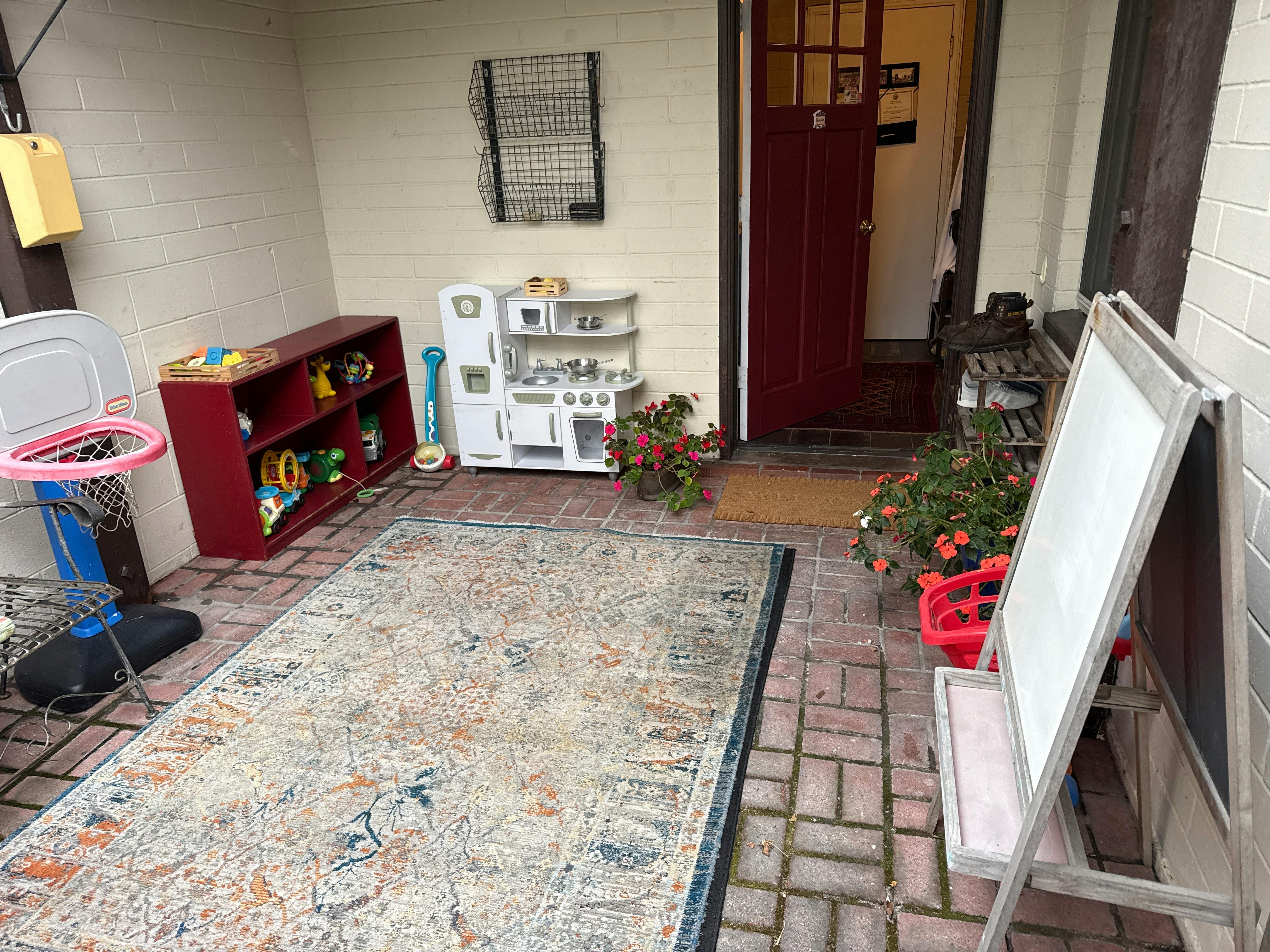 Childrens play area on a brick patio with toys and a whiteboard