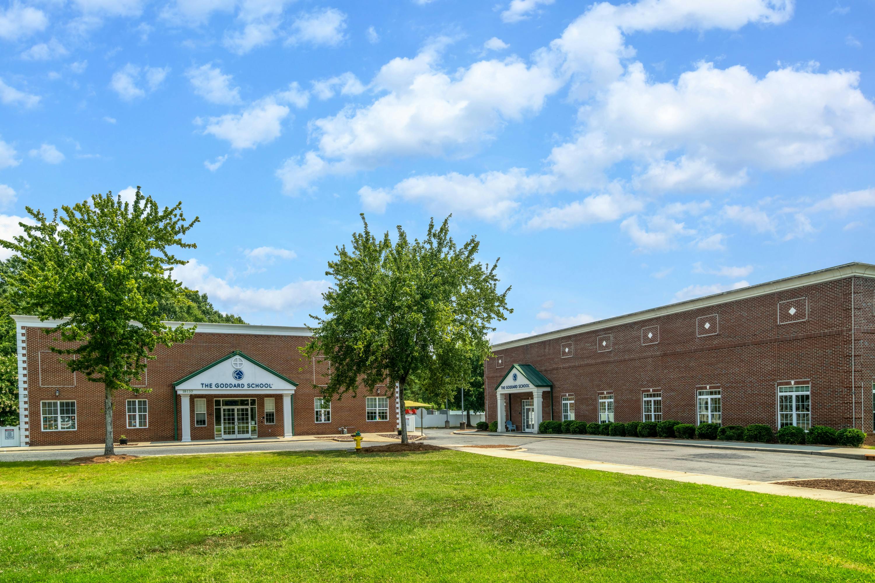 Two brick buildings with green awnings and a grassy lawn