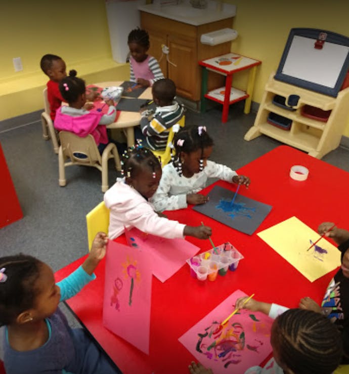 Children painting at tables in a classroom