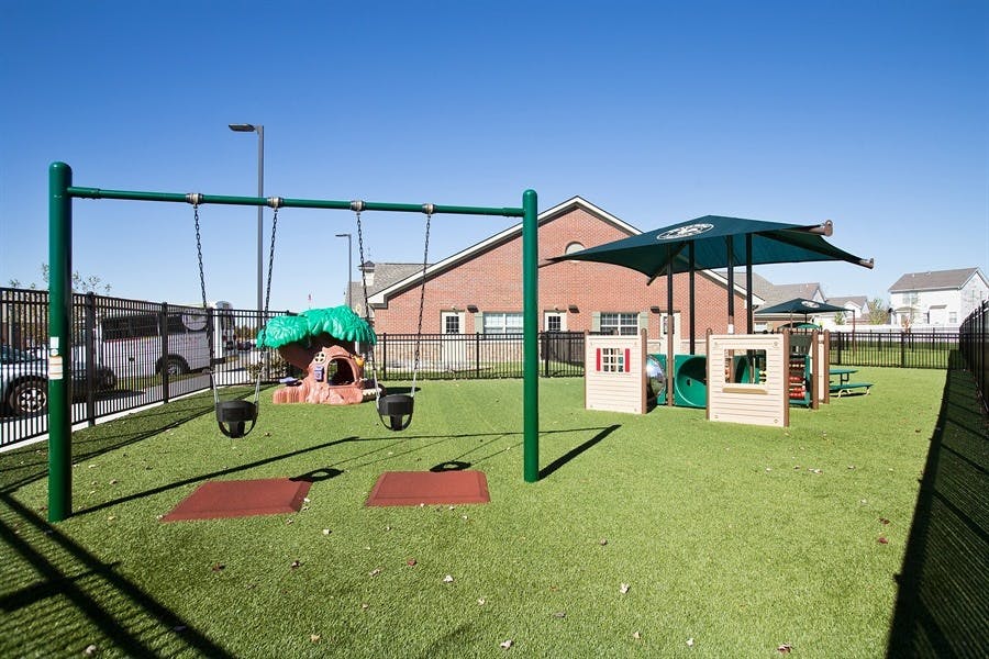 Outdoor playground with swings, play structures, and artificial turf