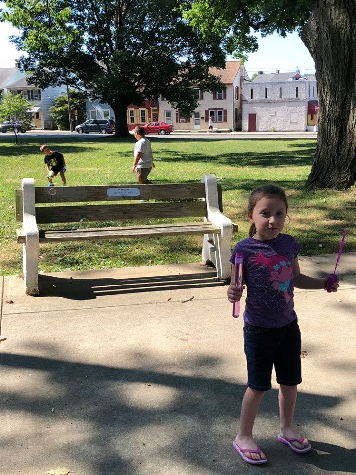 Child holding bubble wands, two children playing in background