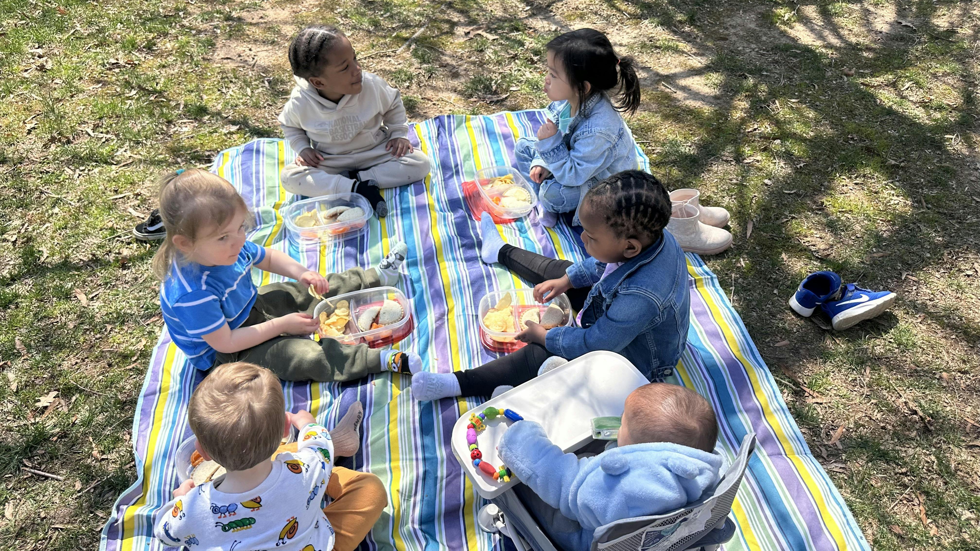 Children and adults on a striped blanket outdoors