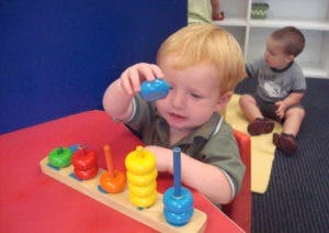 Child playing with a stacking toy at a table