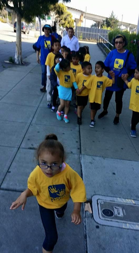 Children and adults walking on a sidewalk