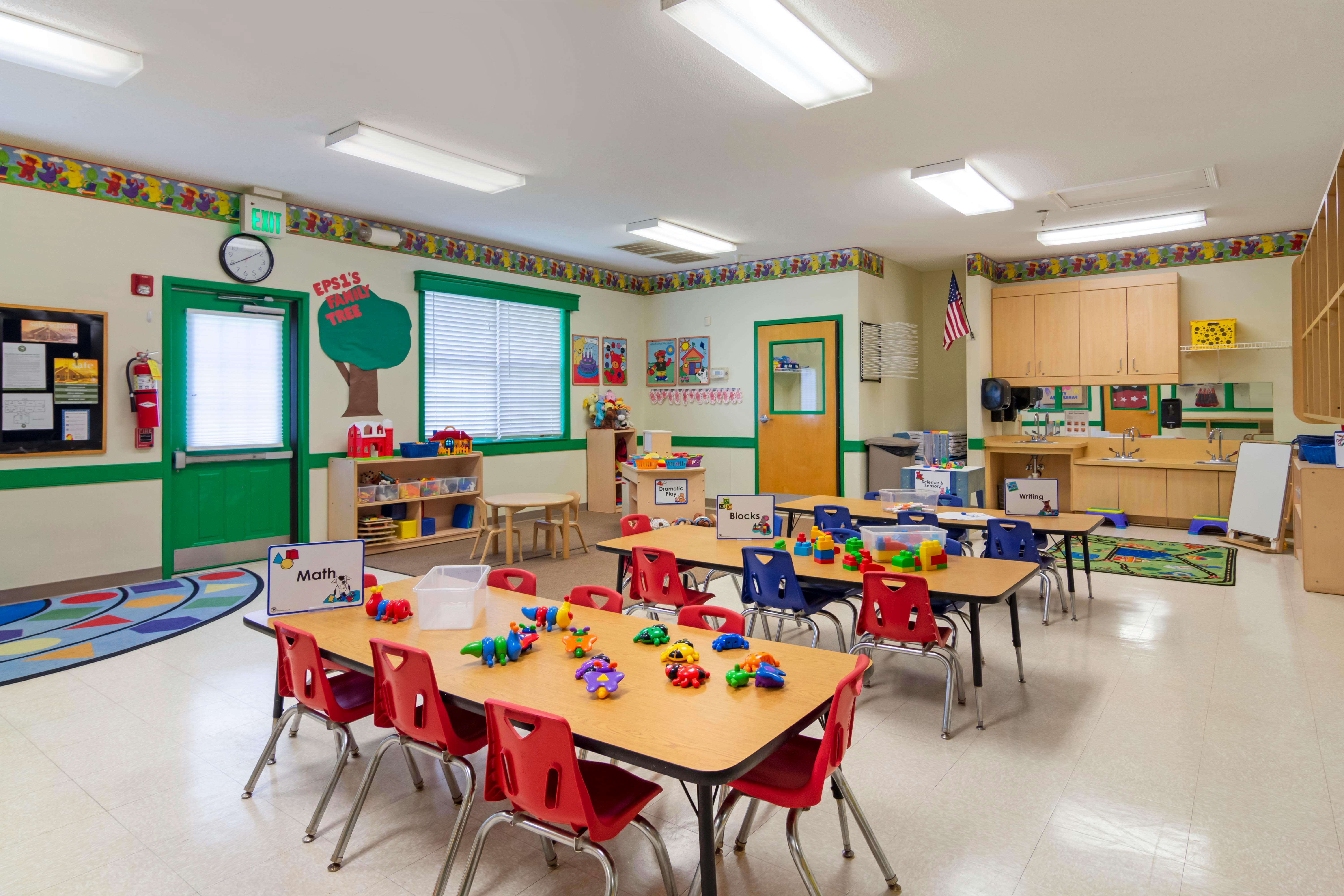 Classroom with small tables and chairs, toys, and learning stations