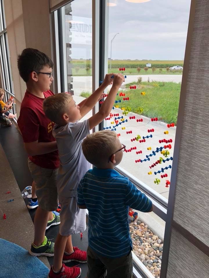 Three children playing with colorful magnetic toys on a window