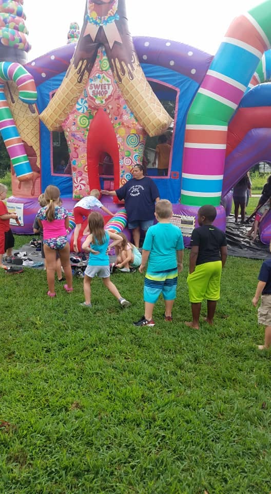 Children playing on a colorful inflatable bounce house with a person supervising