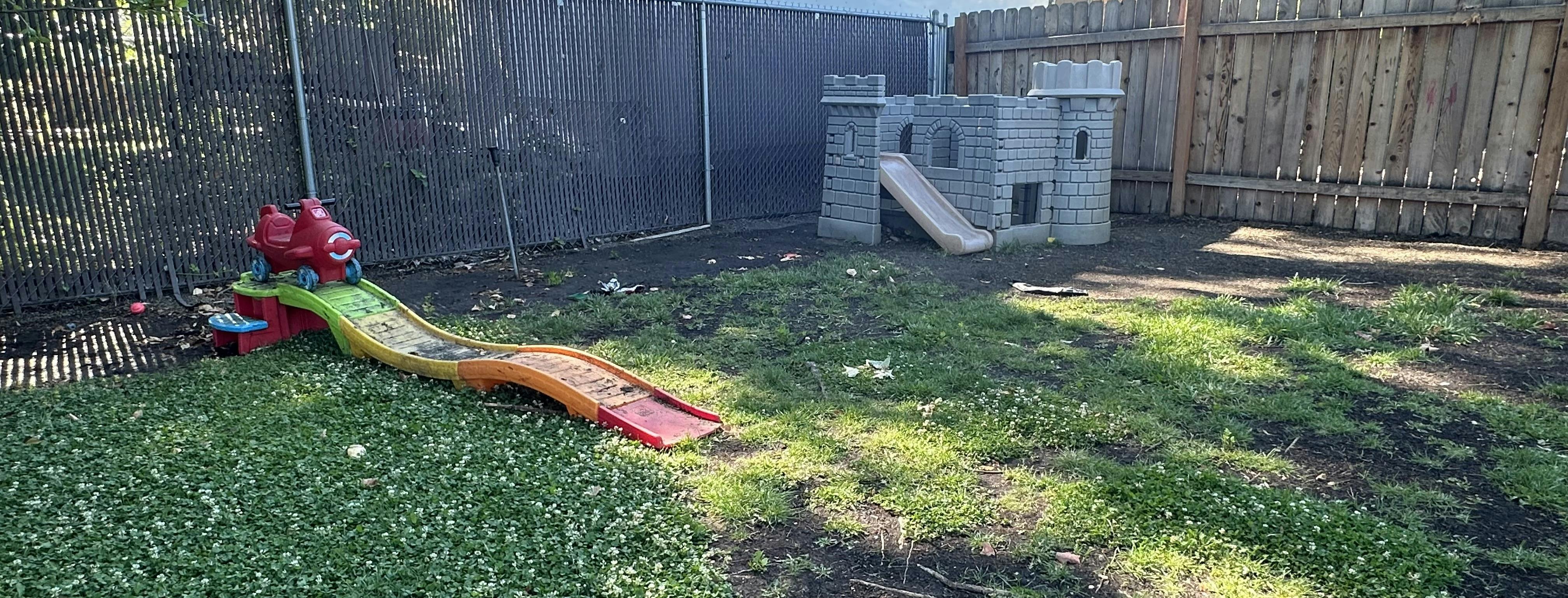 Plastic play equipment including a toy airplane slide and castle in a yard