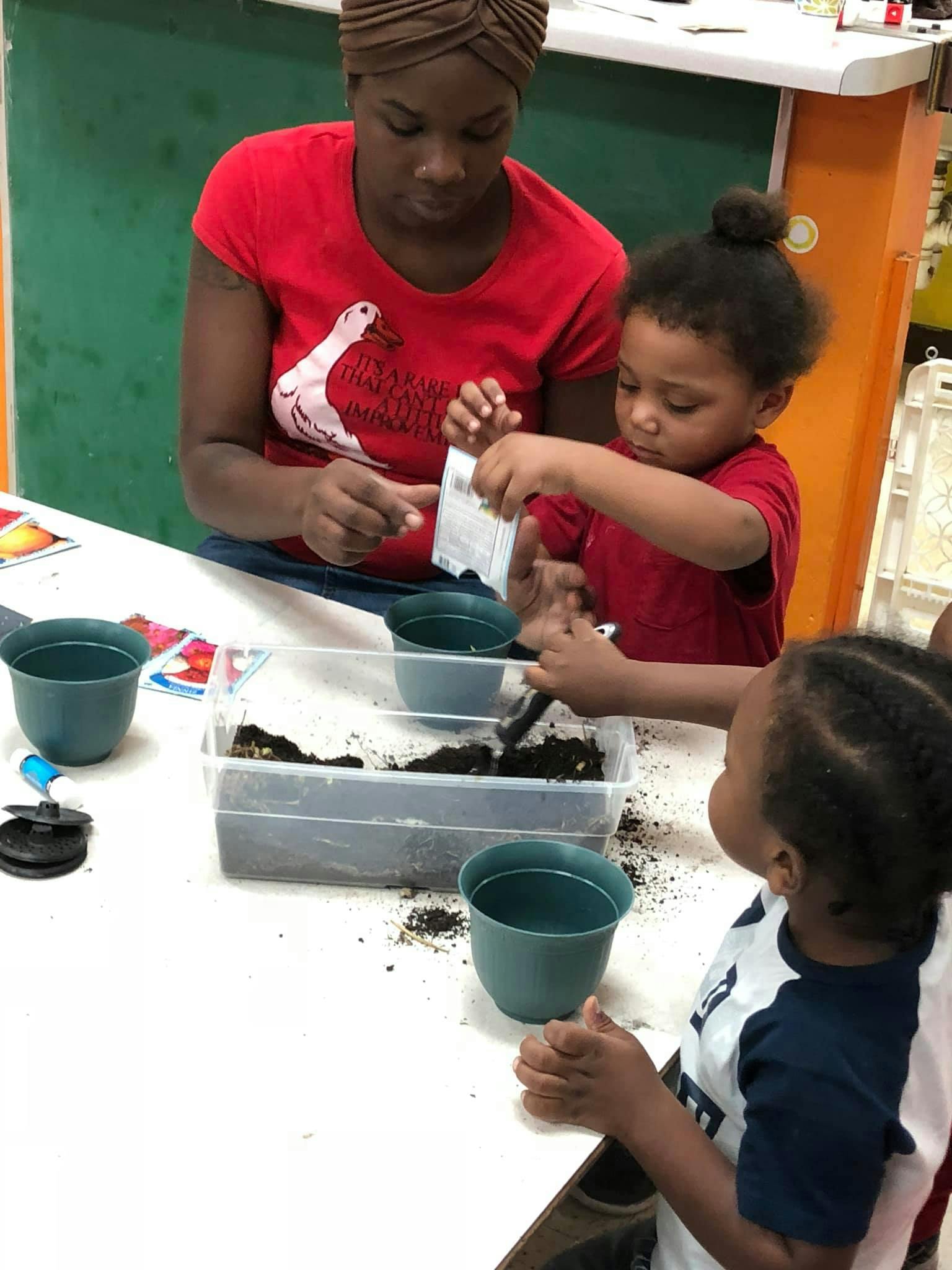 Person and child planting seeds in small pots