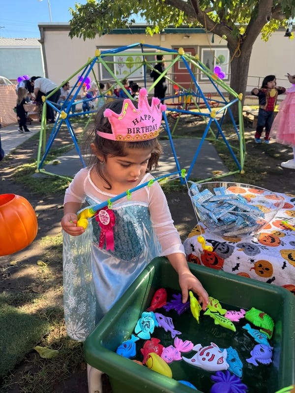 Child in a birthday crown playing a fishing game