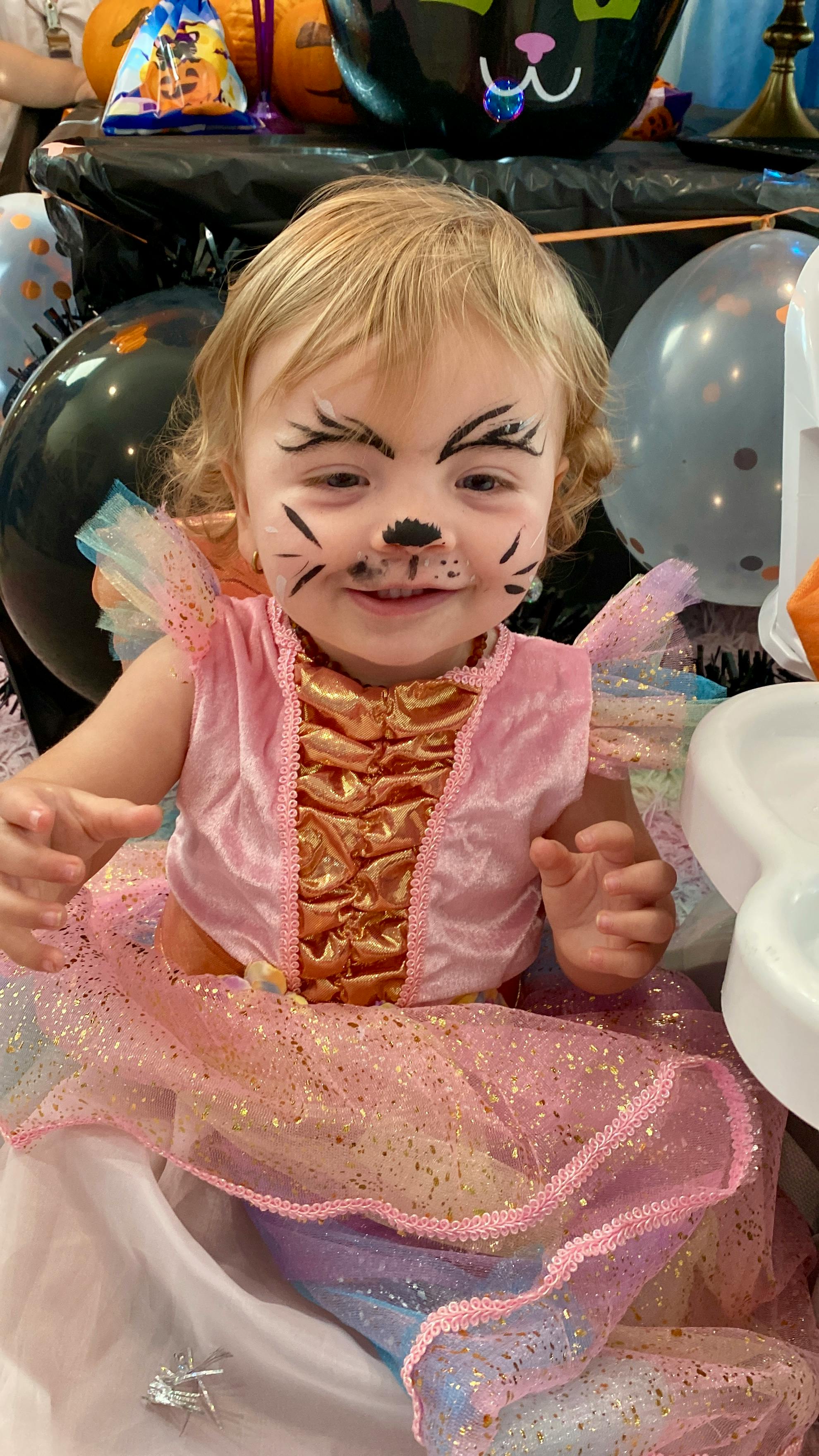 Child in a pink and gold costume with cat face paint