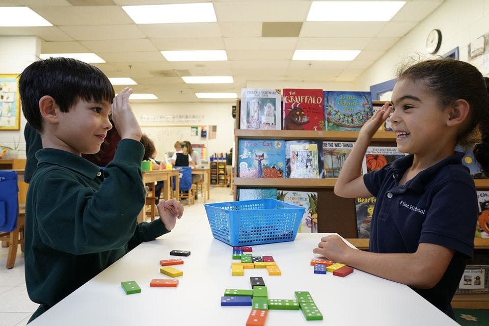 Two children playing with dominoes at a table