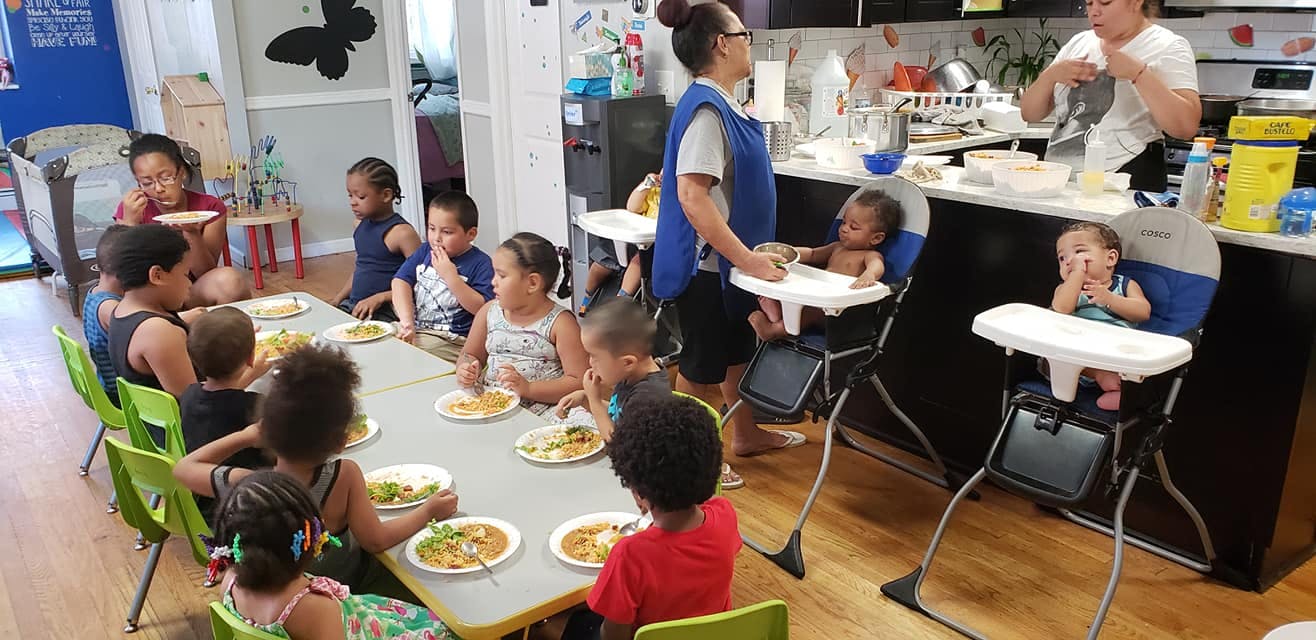 Adults and children eating at a table and in high chairs in a kitchen