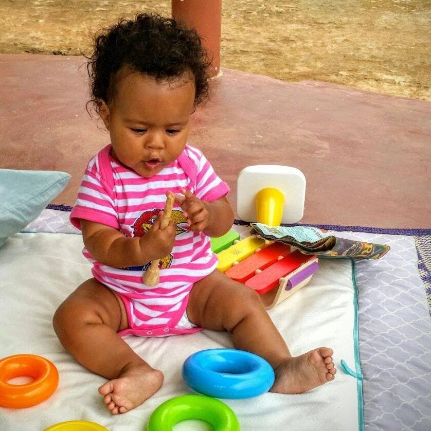 Child playing with a wooden toy and plastic toy