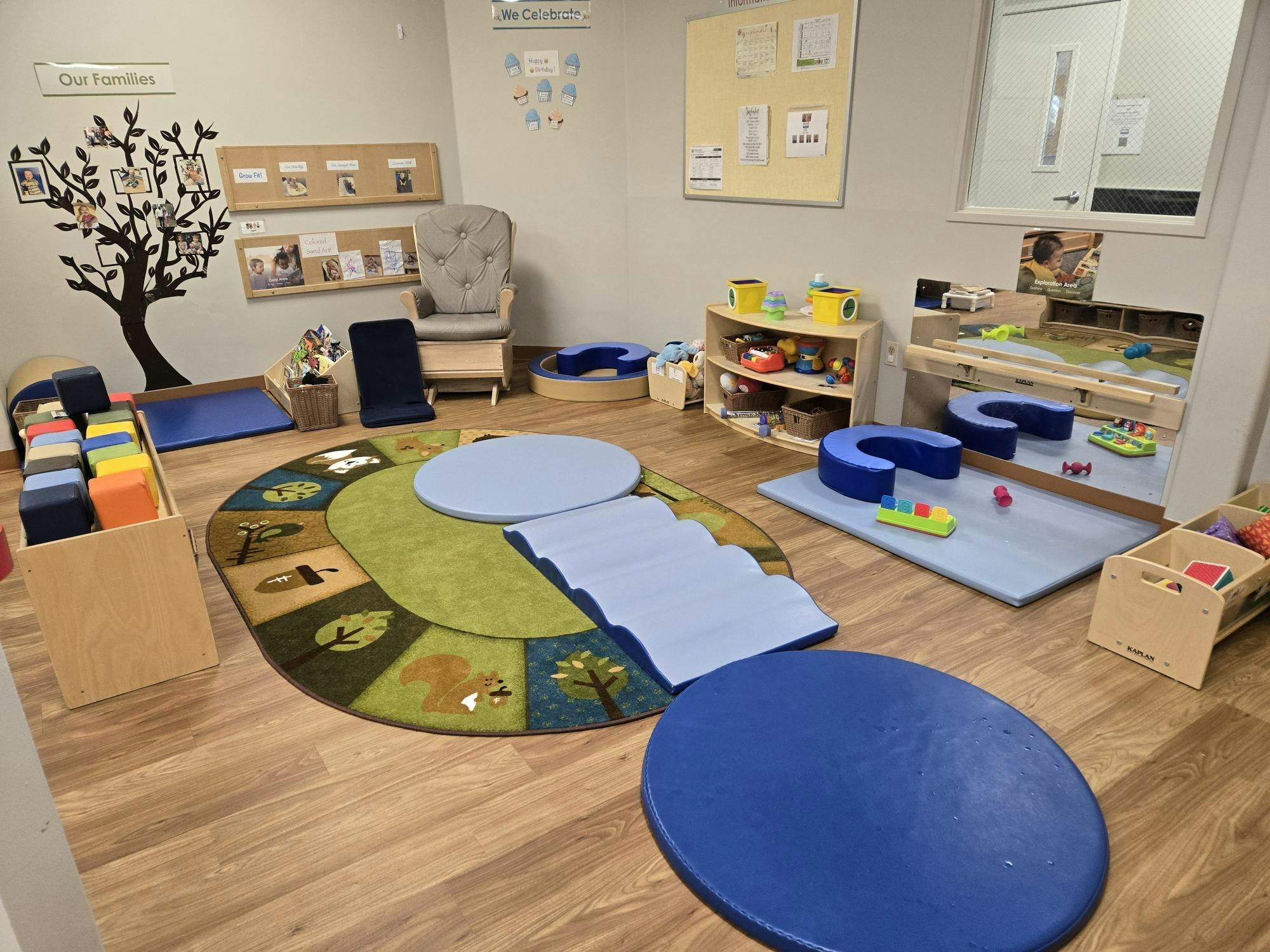 Playroom with a tree decal on the wall, a rug, and various toys
