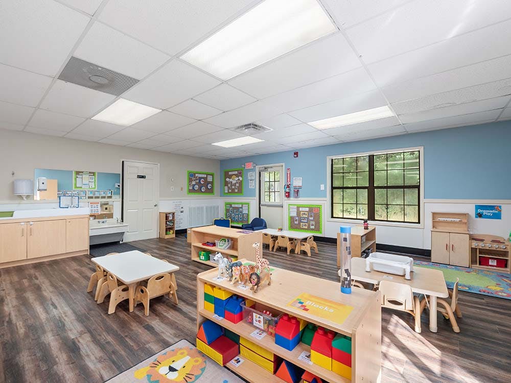 Empty colorful preschool classroom with small tables and chairs