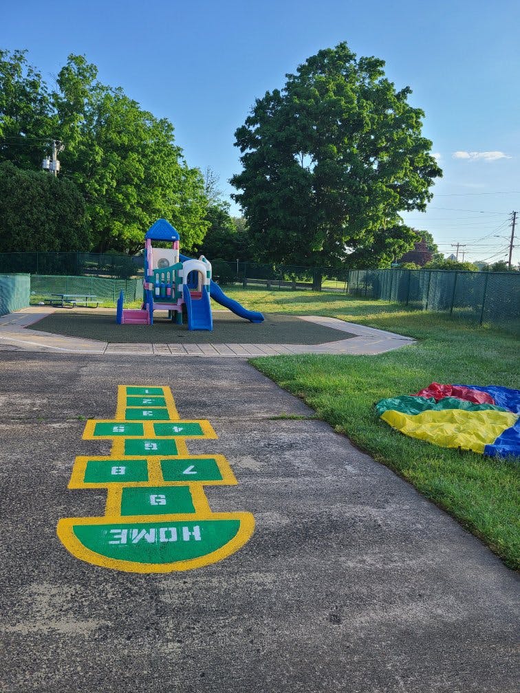 Hopscotch game painted on concrete next to a colorful playground structure