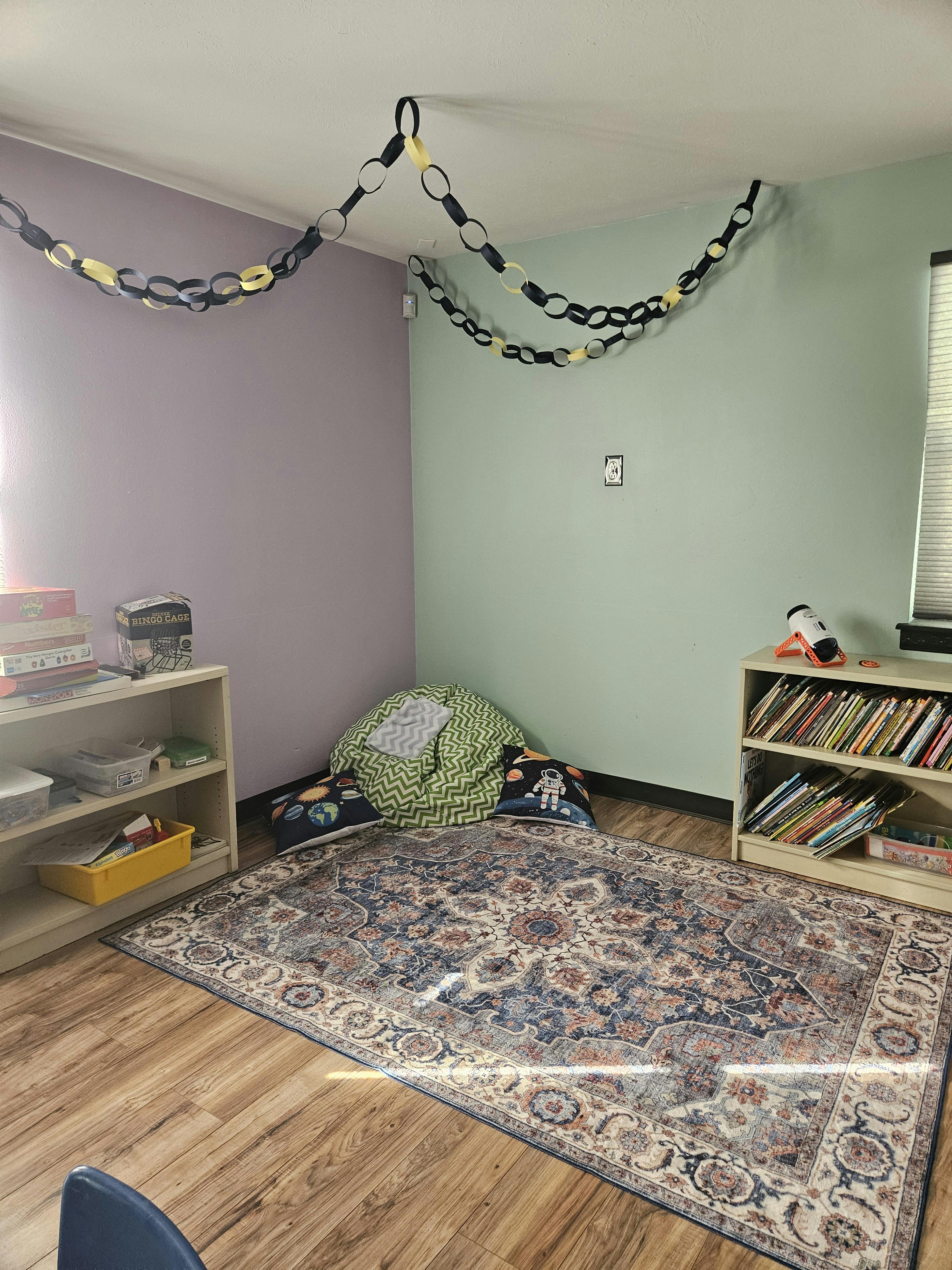 Room with two bookshelves, a patterned rug, and beanbag chairs