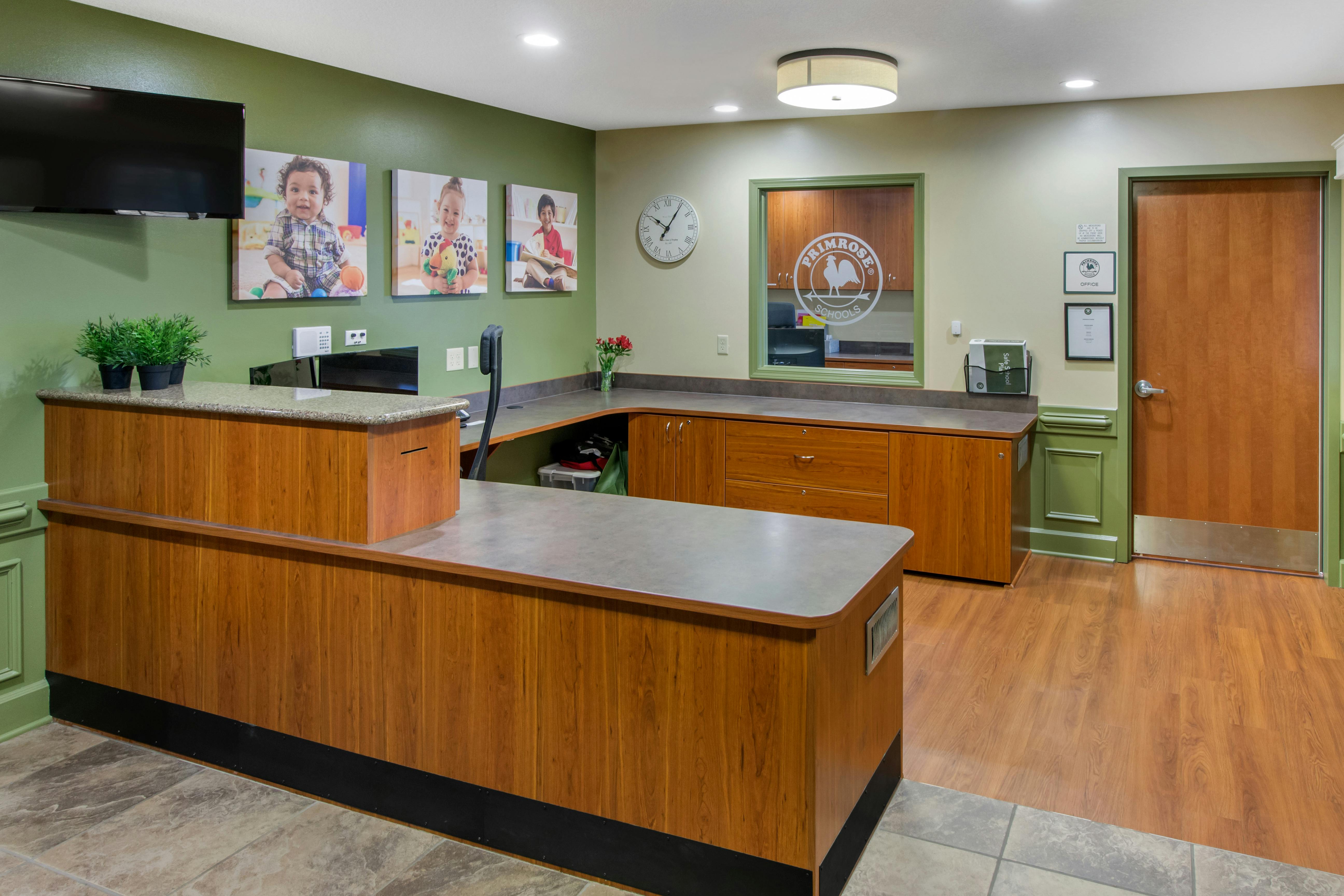 Reception desk with wood cabinets and children's photos on the wall
