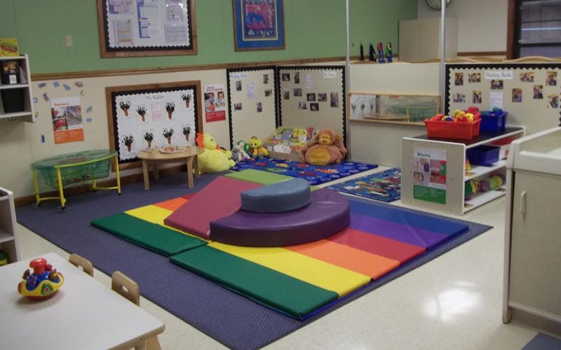 Colorful playroom with soft mats, tables, chairs, and toys
