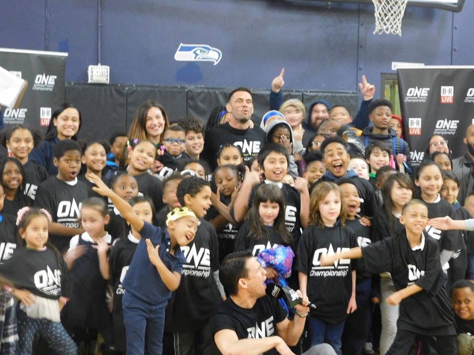 Large group of adults and children in black shirts posing for a photo