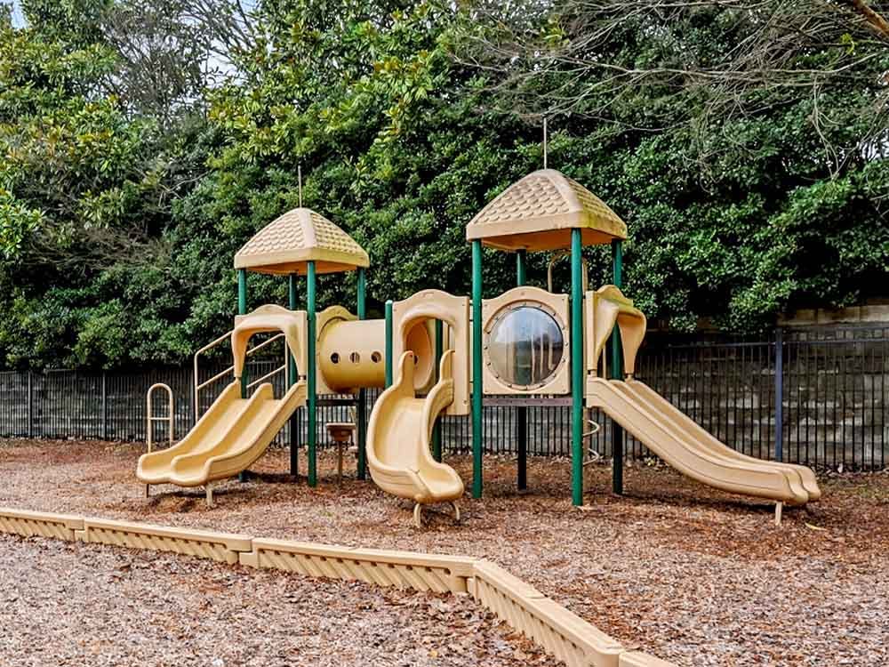 A beige and green playground set with slides and climbing areas