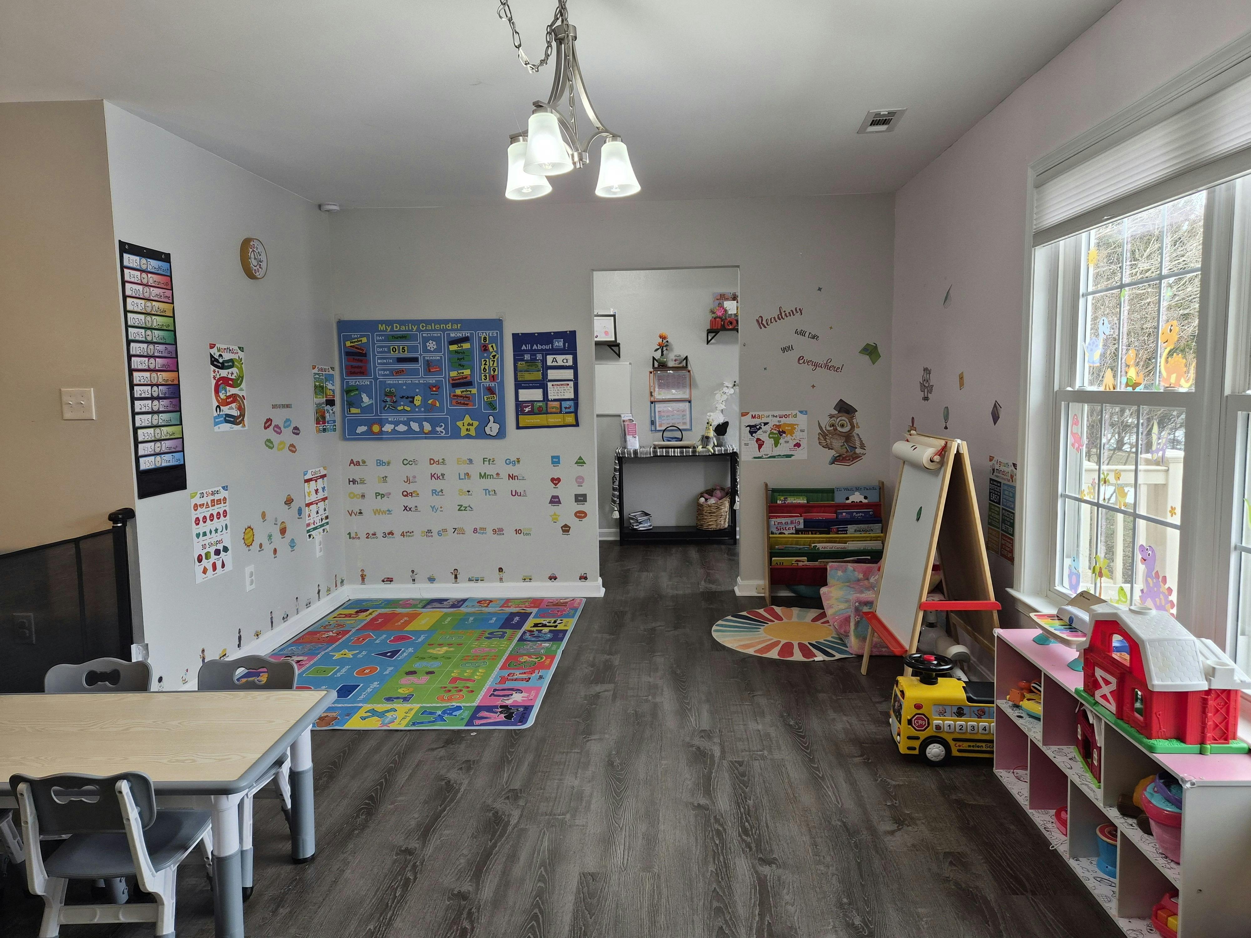Children's play area with a table, chairs, colorful rug, toys, and educational posters