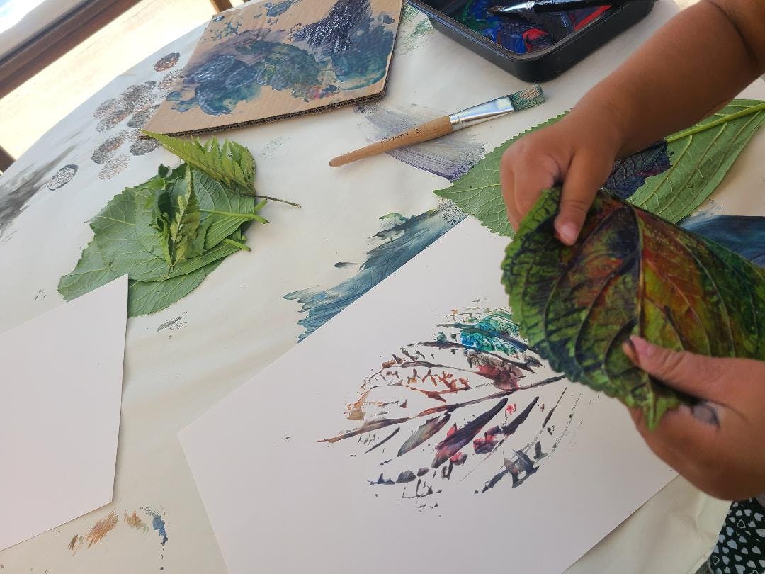 Child making leaf prints with paint on paper