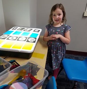 Child standing next to a light table with colorful squares