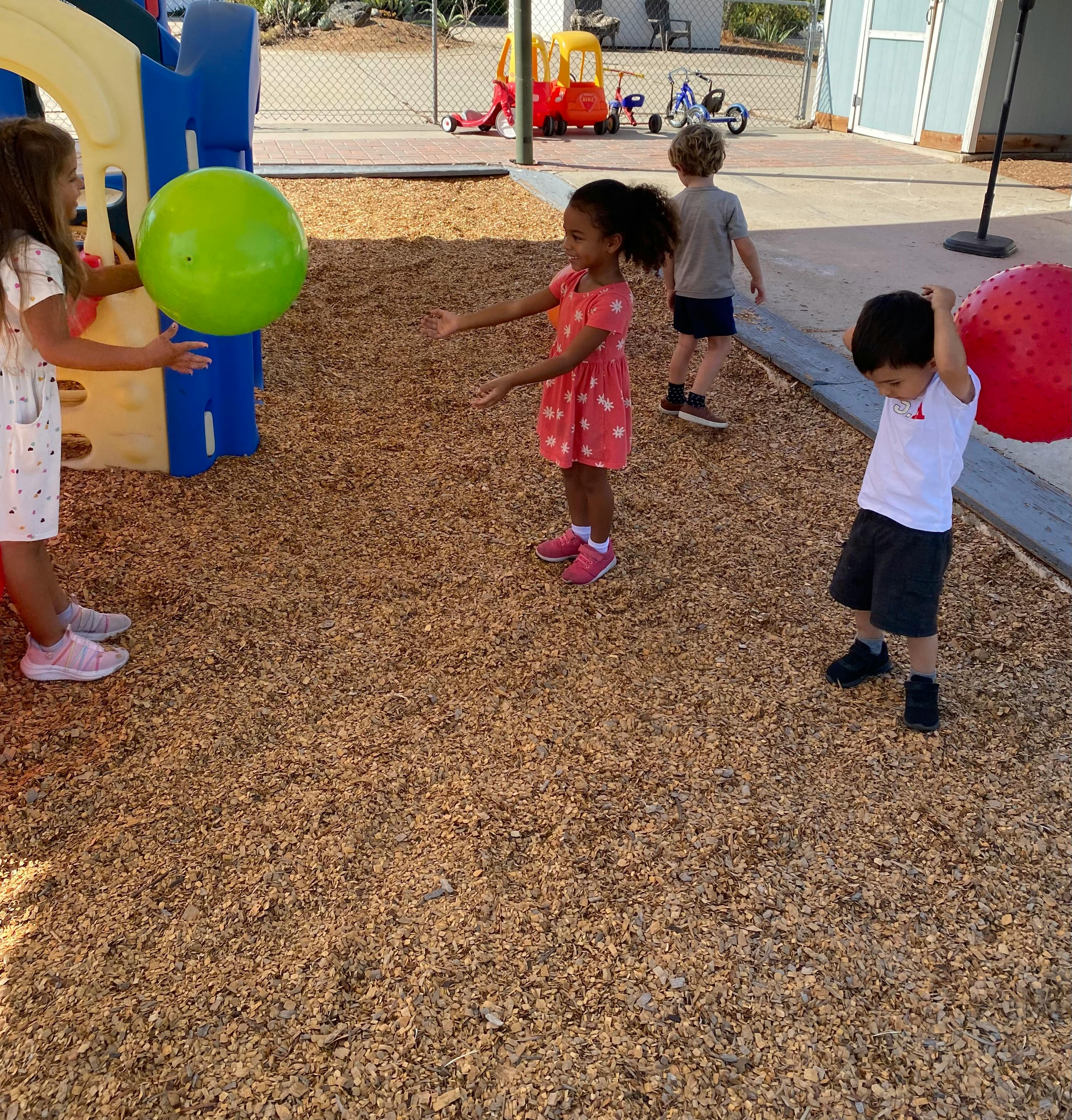 Children playing with balls on a wood chip playground