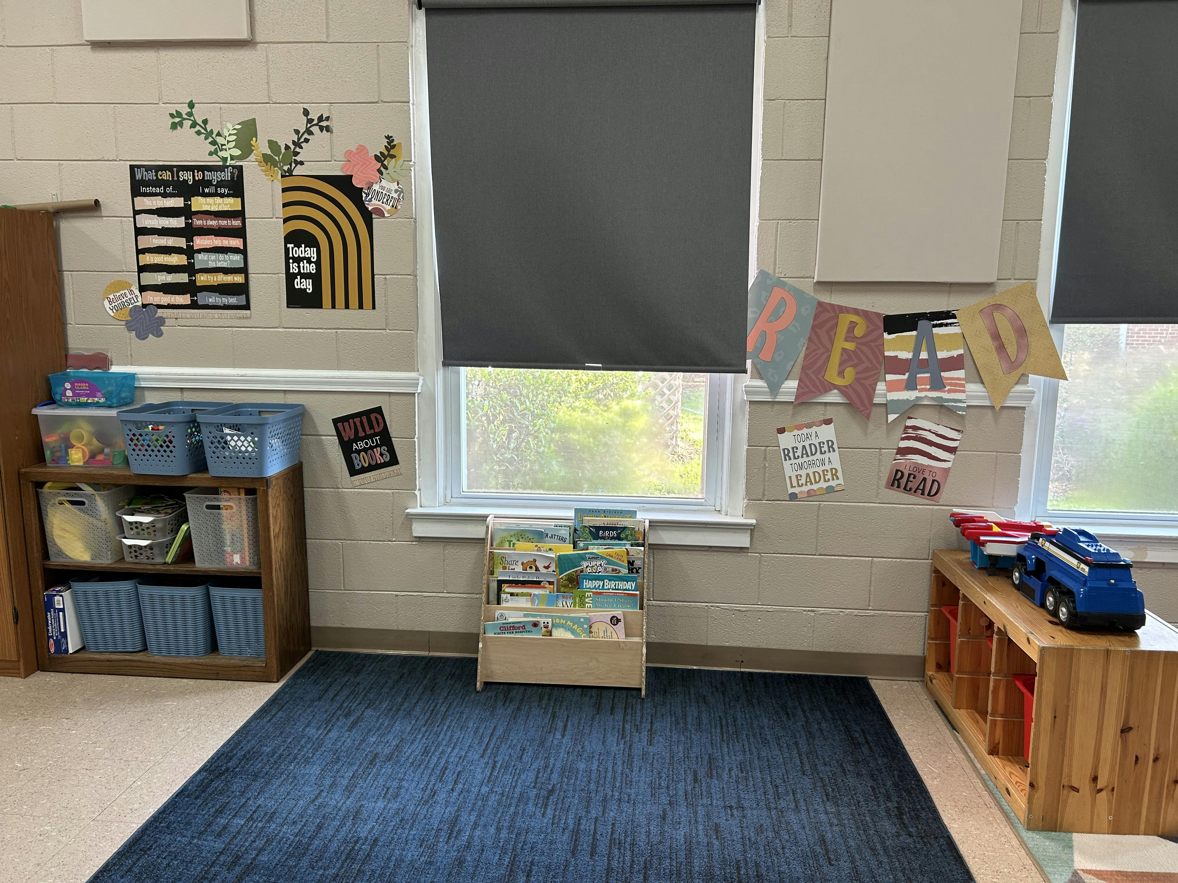 A classroom reading corner with bookshelves, toys, and motivational posters