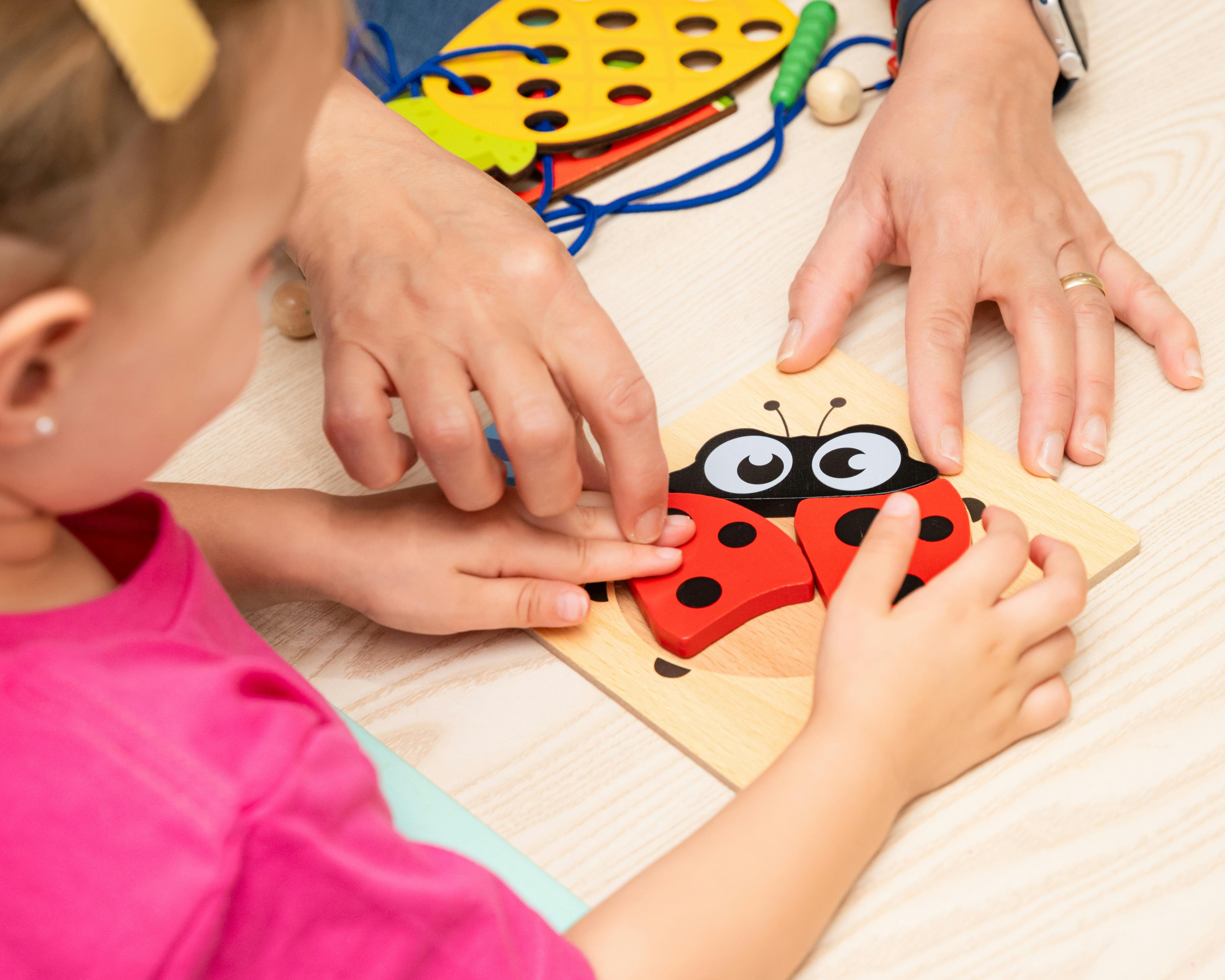 Child and person assembling a ladybug puzzle
