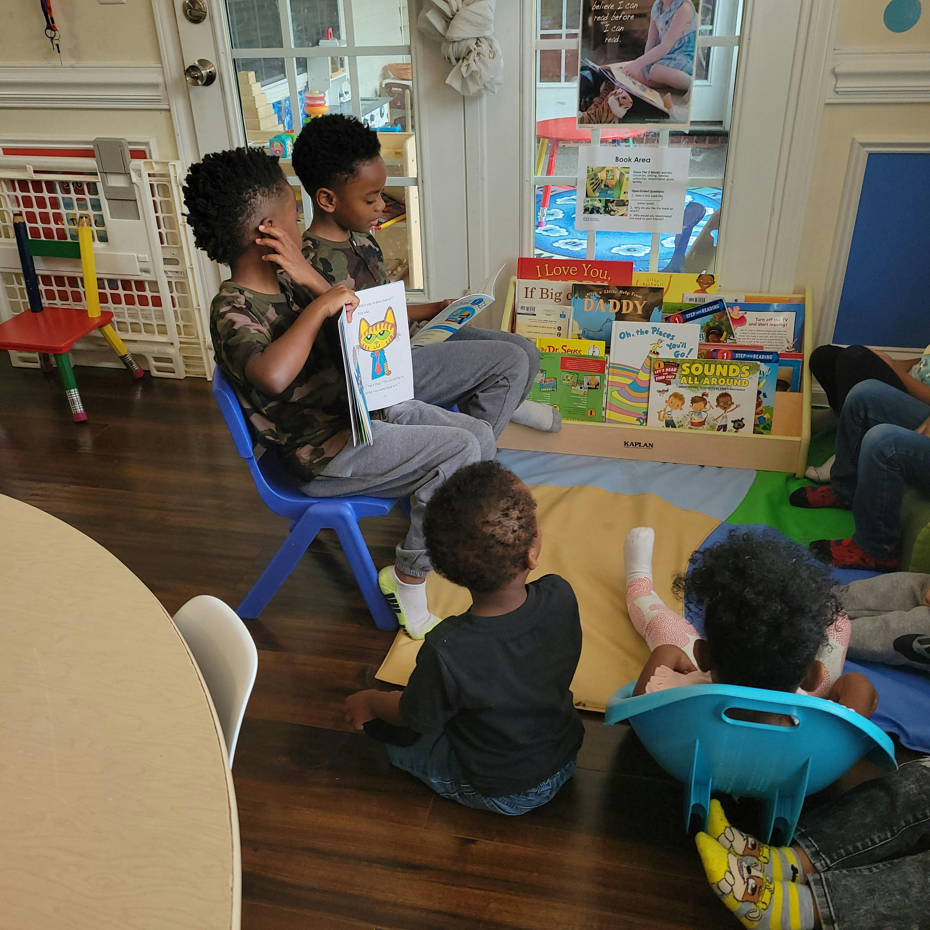 Two children reading a book to other children in a classroom