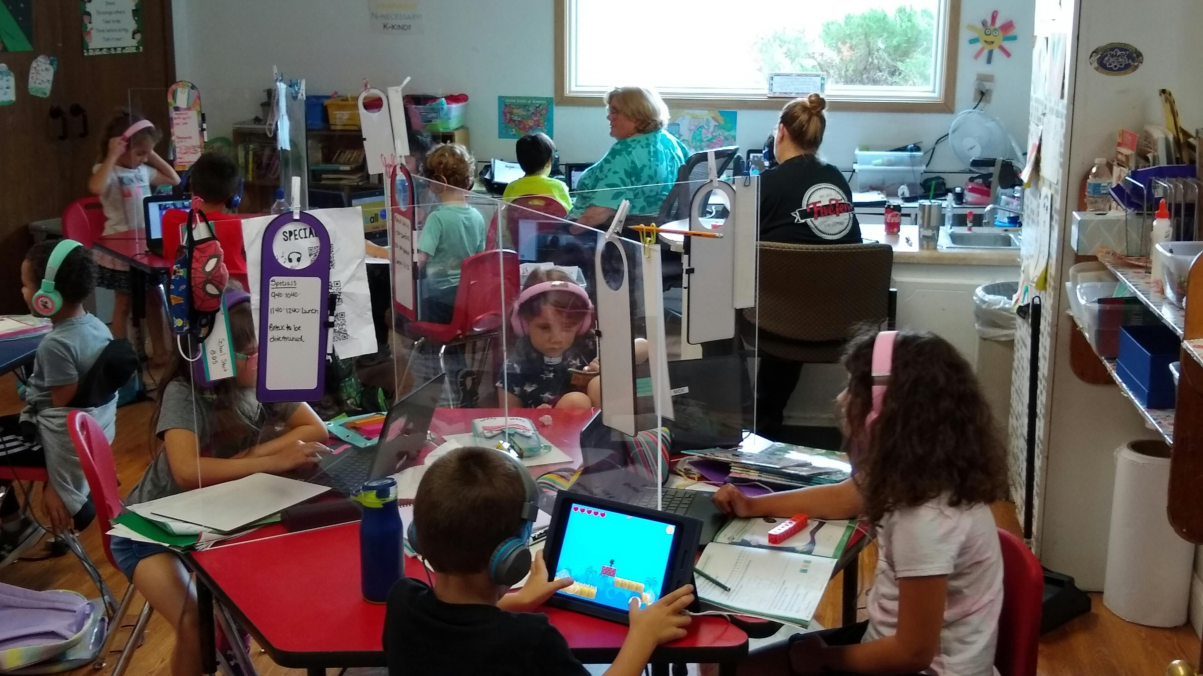 Children in a classroom using headphones and tablets