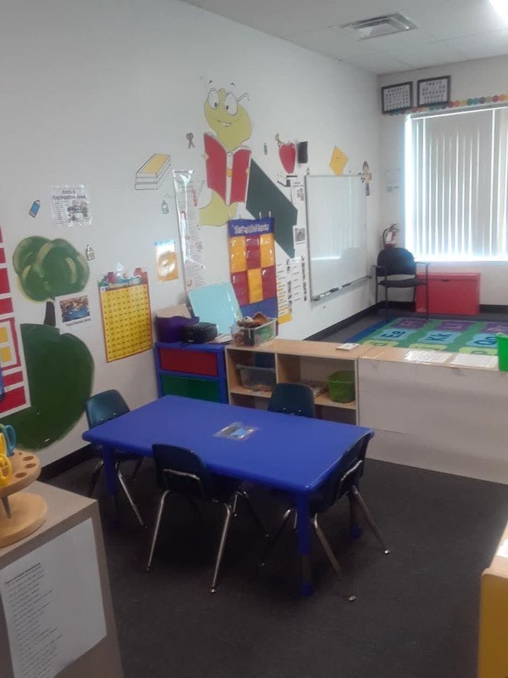 Classroom with a blue table and chairs, colorful wall decorations, and a whiteboard