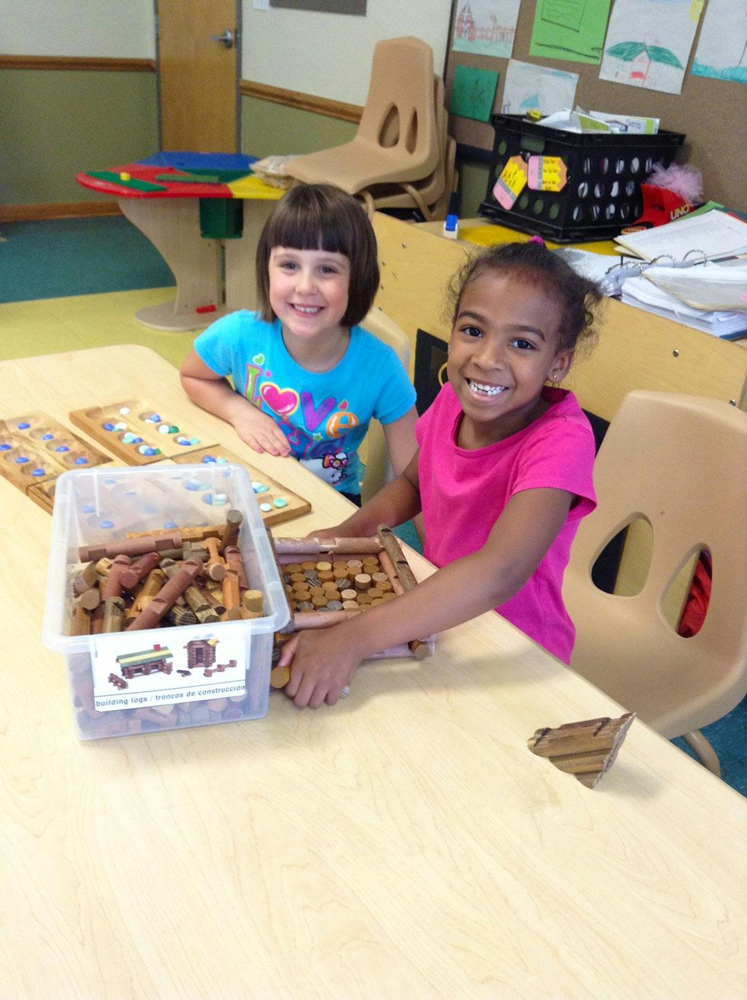 Two children playing with wooden blocks and a board game at a table