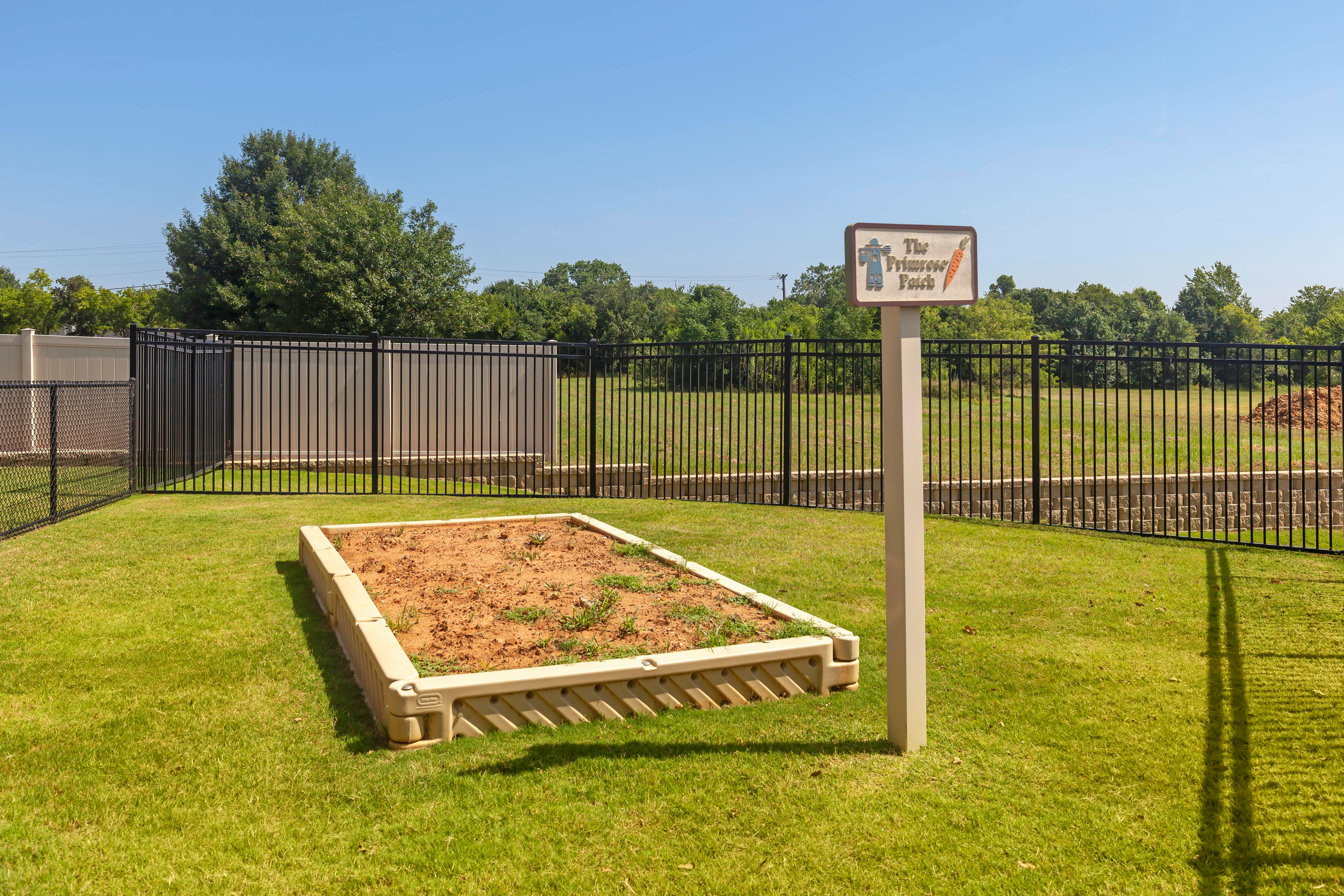 An empty raised garden bed with a sign that reads "The Primrose Patch"
