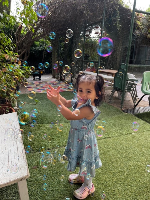 Child with pigtails playing with bubbles outdoors