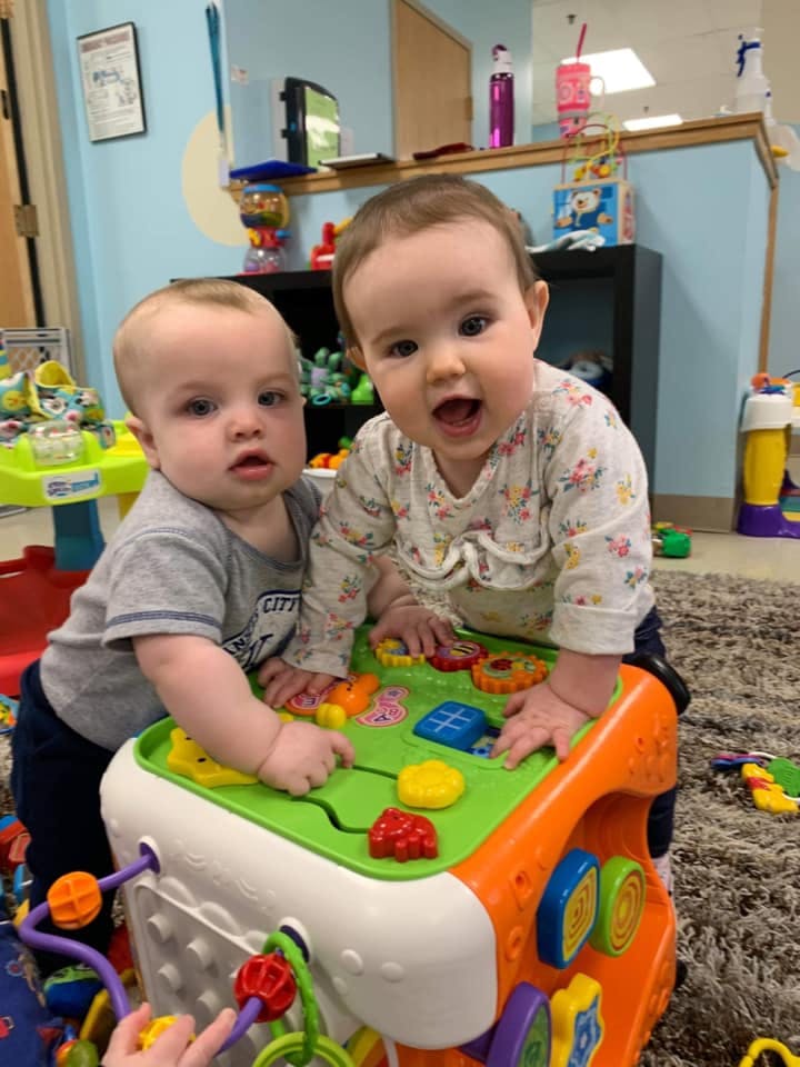 Two babies playing with an activity cube