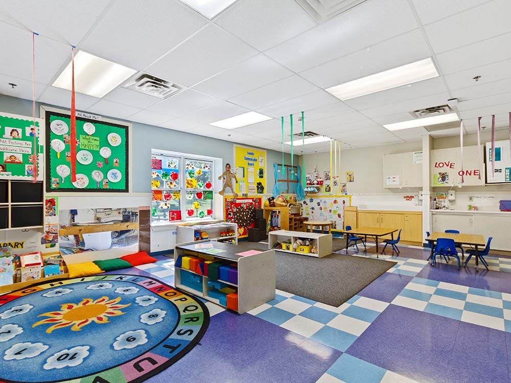 Colorful classroom with a sun rug, cubbies, tables, and decorated walls