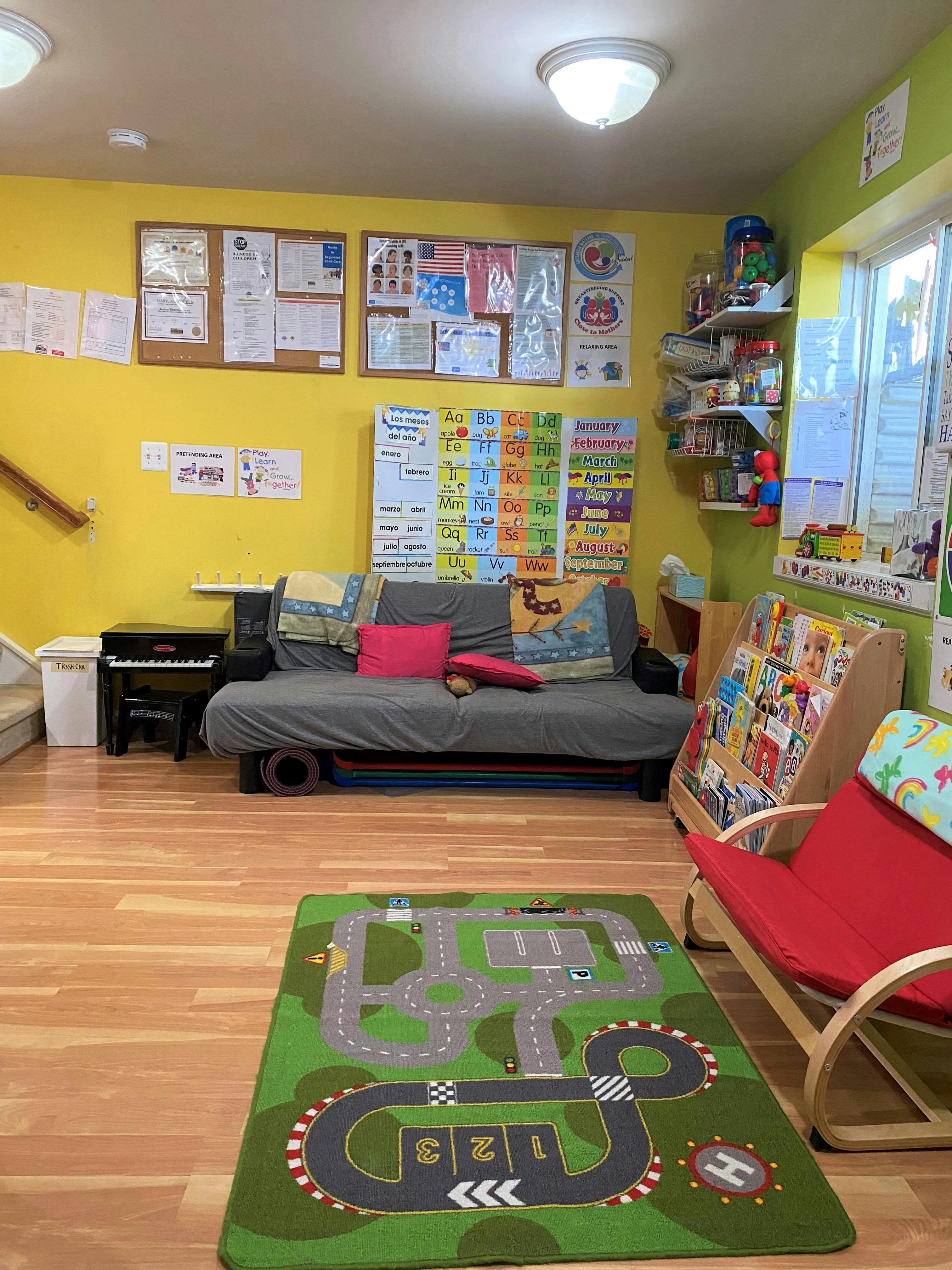 Playroom with a futon, piano, bookshelves, and a road-patterned rug