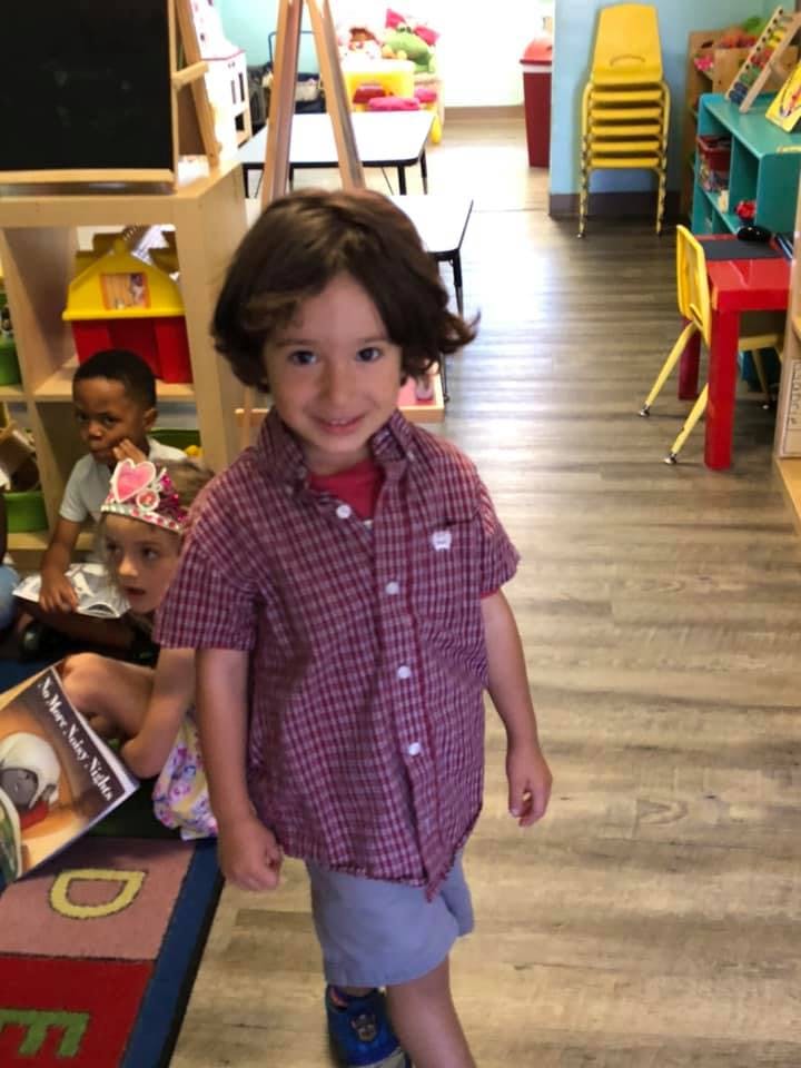 Child in plaid shirt standing in a classroom
