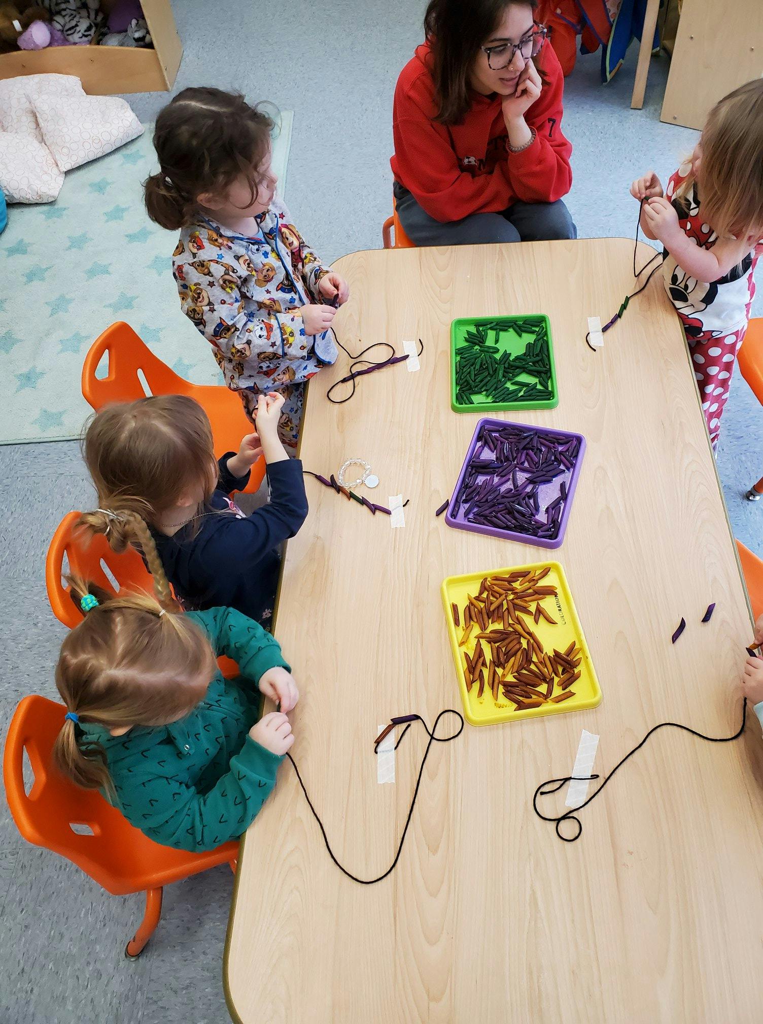 Adult and children at a table with string and craft supplies