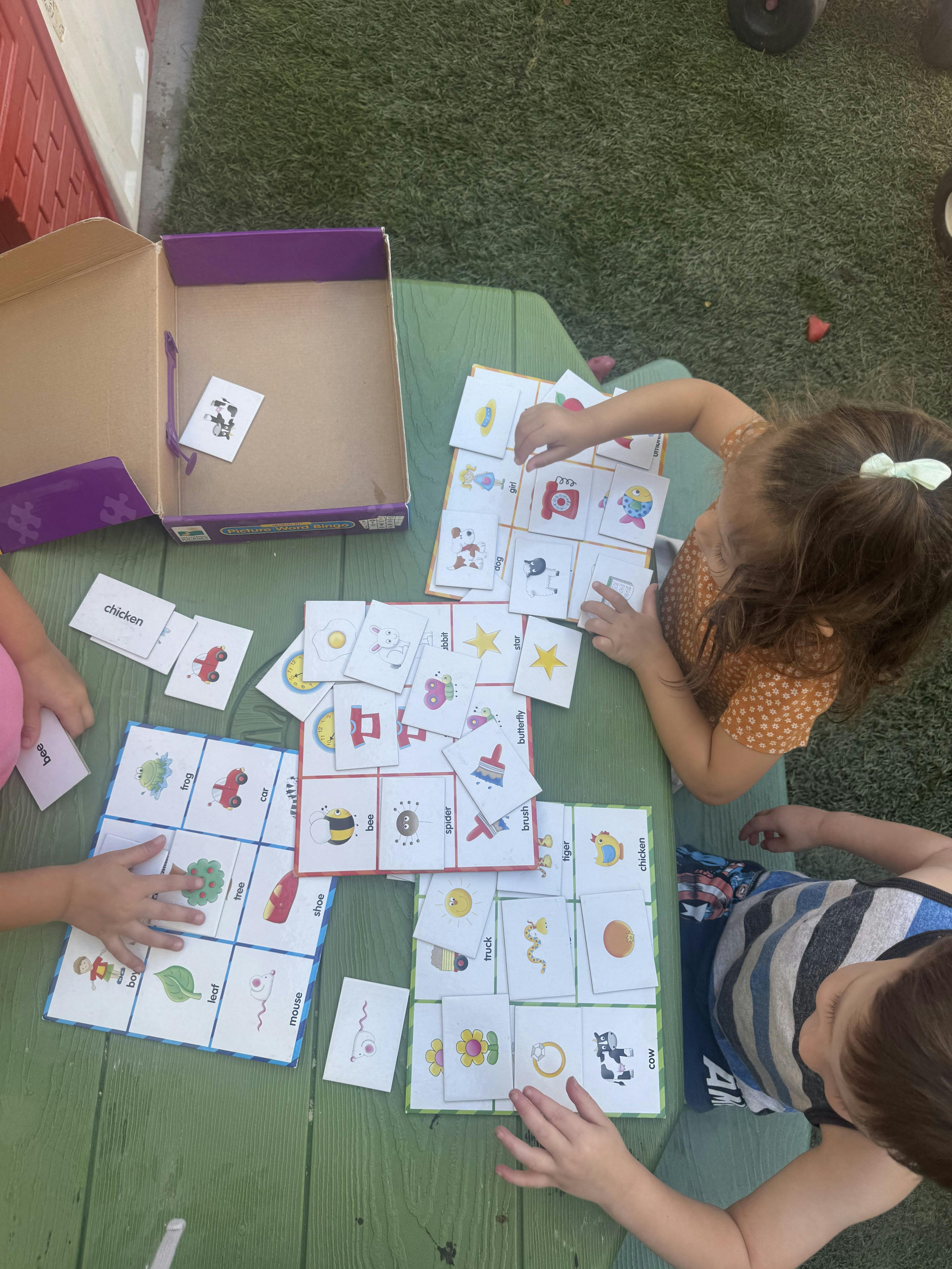 Children playing a card matching game on a green table