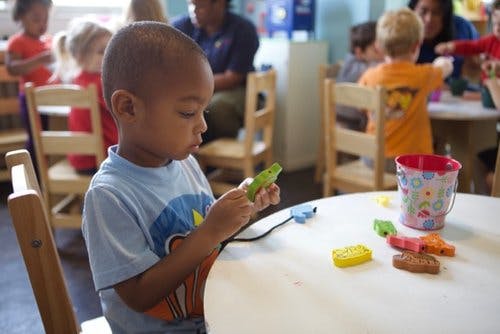 Child playing with toys at a table in a classroom