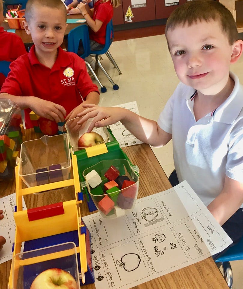 Two children at a table with apples and blocks
