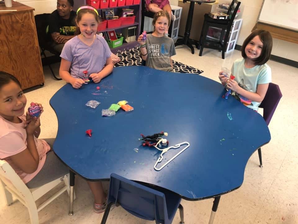 Four children sitting around a blue table in a classroom